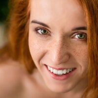 Pure beauty. Cheerful redhead freckled woman laughing at camera